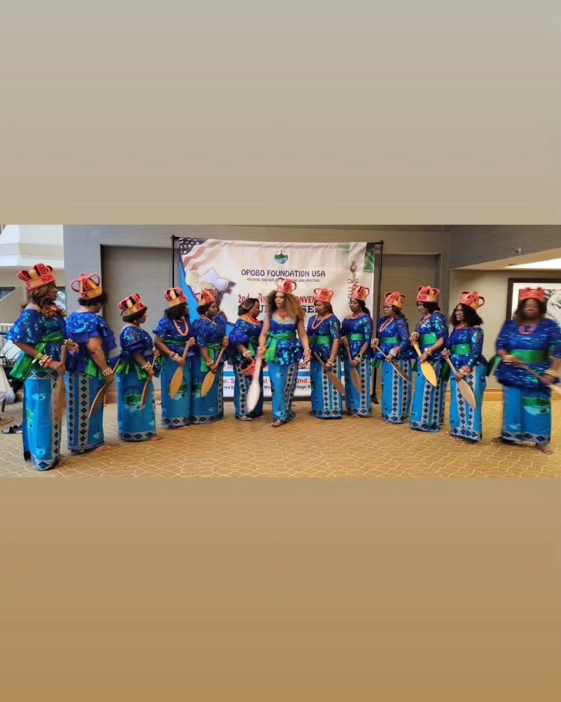 Men of OFUSA in white tunics and teal wrappers at an inauguration banner